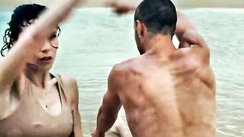 Curly haired brunette in wet tank top reaches for muscular man's ripped back in shallow water