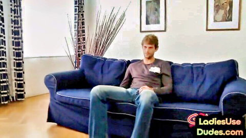 Man in jeans sits on couch for femdom strapon threesome preview