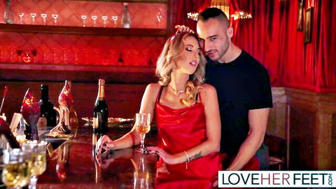 Blonde woman in red dress embraces man at intimate bar, New Year's vibe