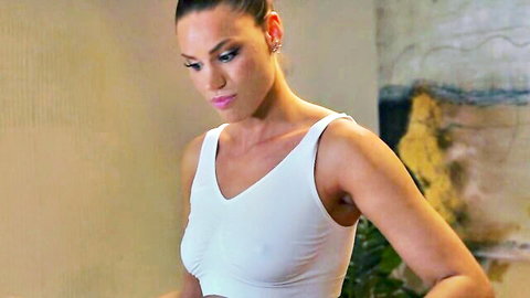 Brunette woman in tight white tank top, intense gaze, devoted to pleasure