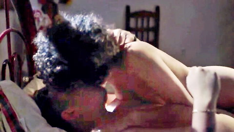 Curly haired nude woman on bed as man passionately sucks her exposed tit