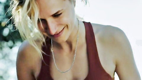 Smiling blonde woman in tight maroon tank top showing cleavage outdoors