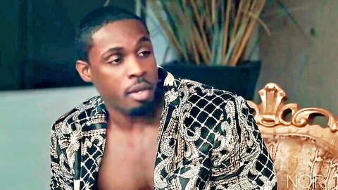 Handsome ebony man in open sequined jacket revealing muscular bare chest on gold throne
