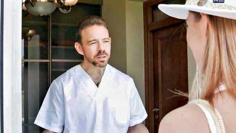 Blonde woman in wide hat chats with doctor in white scrubs at spa doorway