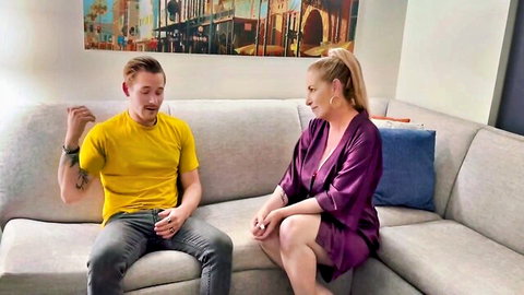 Blonde cougar in purple silk robe with young man on couch