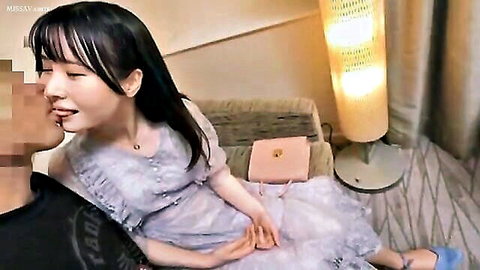 Asian beauty in frilly dress passionately kissing man on couch