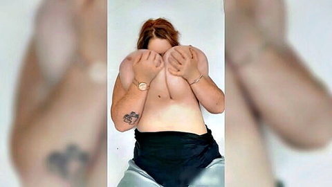 Redhead BBW babe covering her massive natural tits with hands in sexy striptease tease