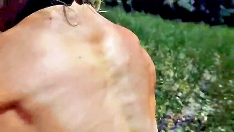 Muscular FBB shows off naked ripped back and glutes outdoors in grassy field