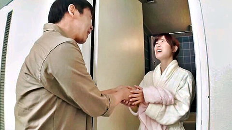 Cute Japanese housewife in white bathrobe smiling at man, holding hands intimately