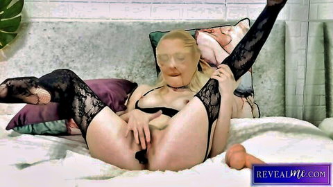 Blonde MILF in black lace stockings spreads legs wide inserting orange dildo into shaved pussy