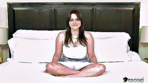 Lilibet Saunders in white tank top and shorts, sitting cross-legged on bed smiling