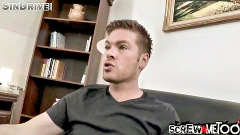 Bearded brunette man in black t-shirt talking on couch in living room adult video.