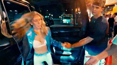 Blonde babe with long hair in shiny blue jacket flashing white bra tits holds hands with guy by open car door at night