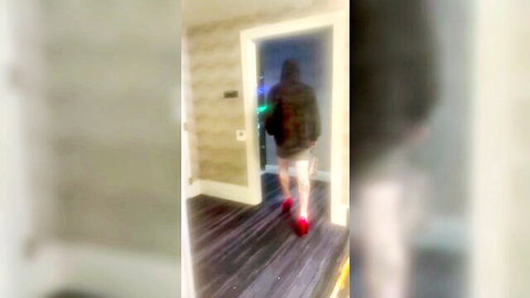 Blurry crossdresser in hoodie and shorts walking through doorway