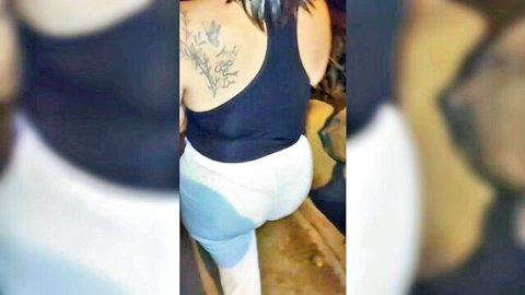 Curvy older woman in tight white leggings and black top, tattooed shoulder