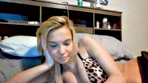 Blonde babe with glasses lies topless in leopard print thong exposing perky tits on webcam bed