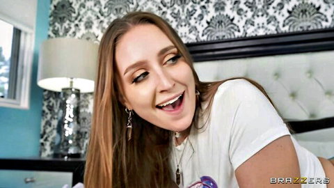 Smiling young brunette with open mouth lying on bed in white t-shirt teasing