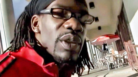 Handsome black man with dreadlocks, glasses, intense expression in red jacket
