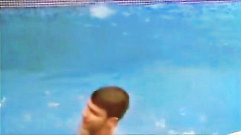 Blurry thumbnail of man with short dark hair emerging from pool water
