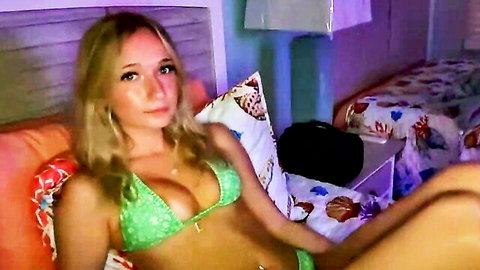 Blonde cam model RoxyRain2736 in green bikini with tan lines, seductive pose