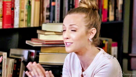 Kiara Cole smiles seductively in library, blonde hair in bun, soft tease