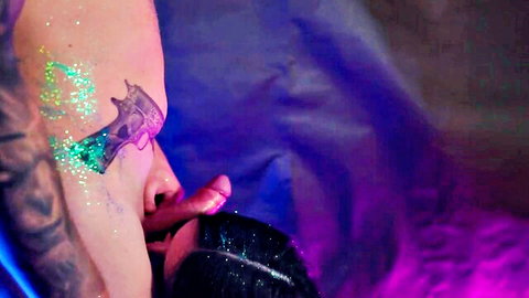 Brunette with glitter tattoos giving blowjob in photo shoot scene