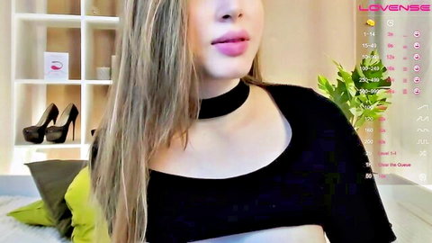 Young blonde camgirl with plump glossy lips pouting in black choker top teasing on Lovense webcam