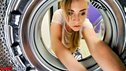 Blonde babe leaning into washing machine, cleavage in white tank top