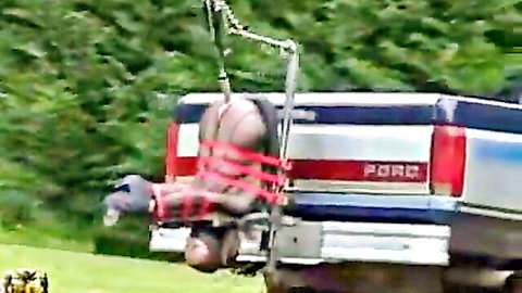 Nude hooded slave bound in red ropes hanging upside down from Ford truck bed exposing ass and pussy outdoors