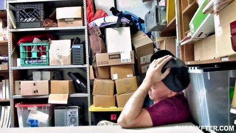 Ecstatic man in black hat clutching forehead intensely in cluttered storage room