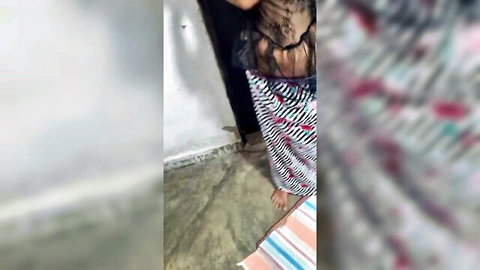 Sri Lankan wife in sheer black top and striped skirt posing teasingly in bedroom doorway
