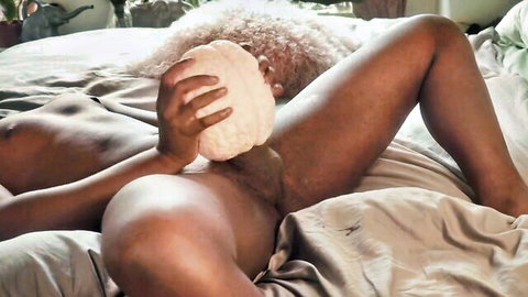 Ebony babe with curly afro spreads legs and presses white masturbator sleeve on her pussy