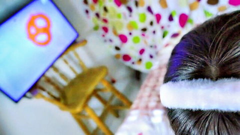 Brunette babe back view wearing fluffy white headband facing pretzel logo TV in colorful polka dot bedroom