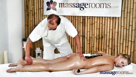 Oiled blonde babe lies naked prone with ass exposed getting foot massage in erotic massage room