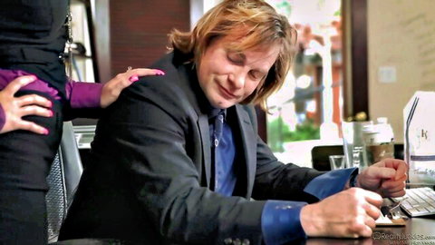Evan Stone in suit at desk with seductive woman gripping his shoulders teasingly
