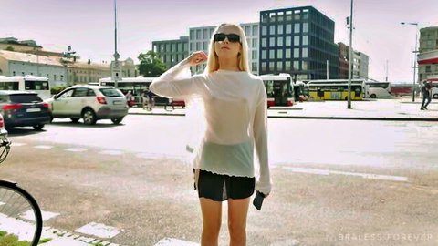 Emma White braless in sheer white top and black shorts, urban outdoor pose