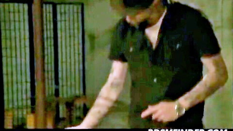 Tattooed dominant man in open shirt preparing BDSM torture on bound teen