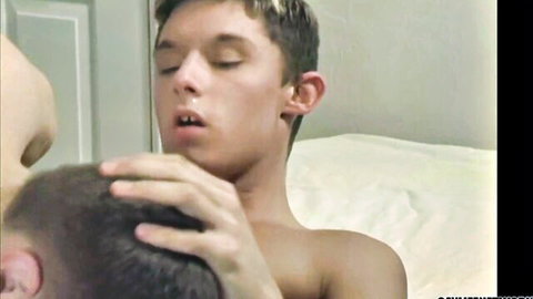 Young twink with open mouth getting blowjob while head gripped by another guy