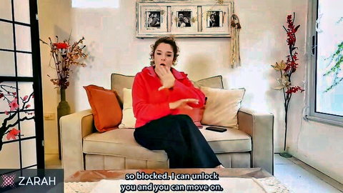 Clothed brunette MILF gesturing seductively on couch with open mouth and hands