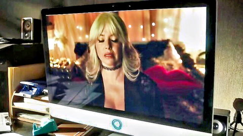 Blonde bombshell with massive tits in deep cleavage black top seducing on porn video screen