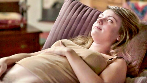 Blonde pregnant woman relaxing in tank top, hand on belly
