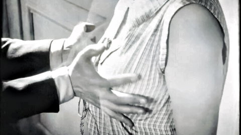 Vintage B&W scene of suited man groping woman's breasts through checkered dress