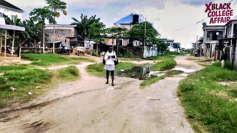 Black college teen in short skirt walking dirt road near X Black College Affair