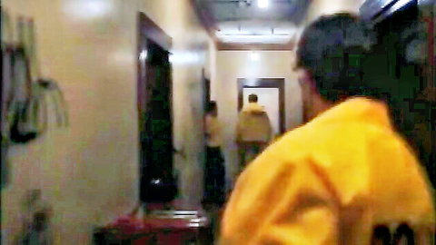 Blurry man in yellow jacket with number 20 walks down indoor hallway with others behind
