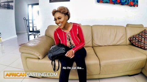 Smiling African babe in revealing red lace-up top on casting couch