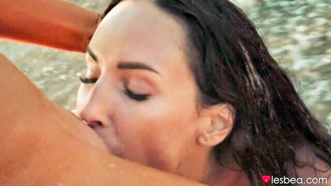 Brunette lesbian sucking wet pink nipple outdoors on beach