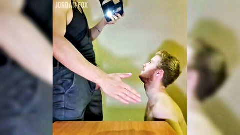 Muscular gay dom in tank top films redhead sub kneeling shirtless with open hand to his begging face