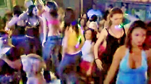 Crowd of sexy women dancing in revealing outfits at wild neon party