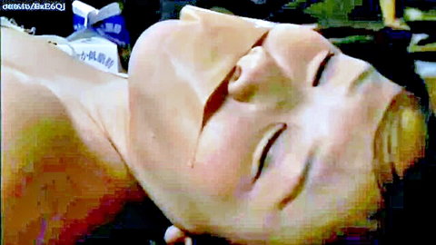 Japanese woman in white face mask lying exposed, eyes closed in escape scene