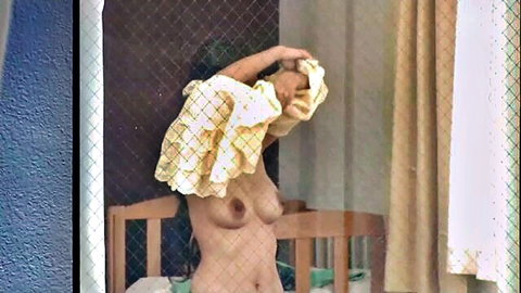 Busty Asian woman topless, changing clothes through window voyeur view